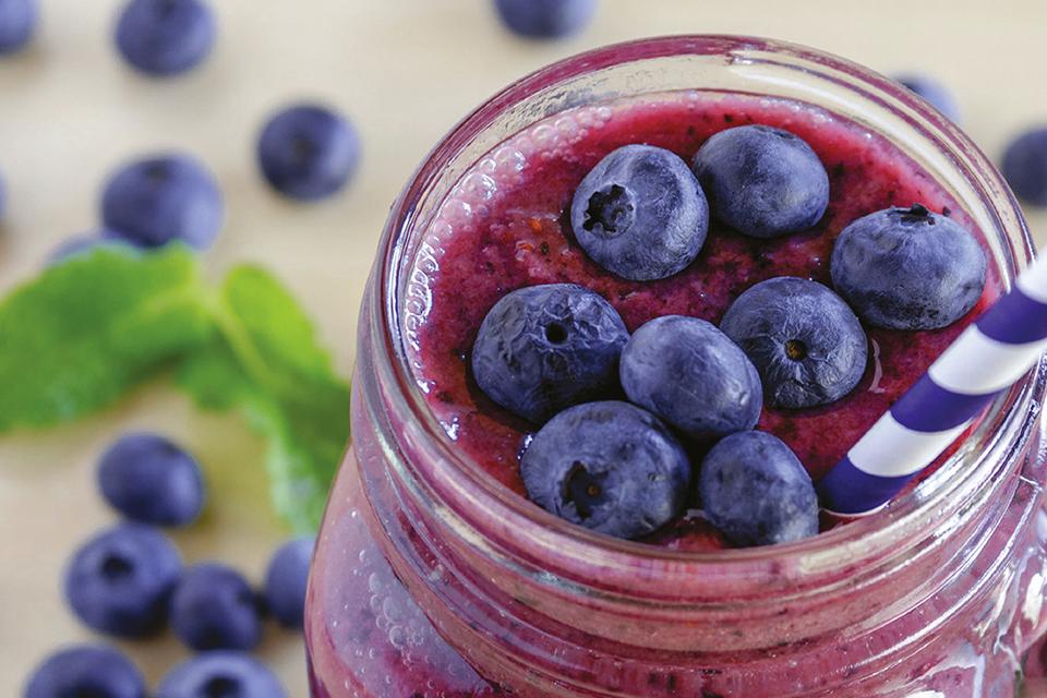 A blueberry smoothie with blueberries scattered around.