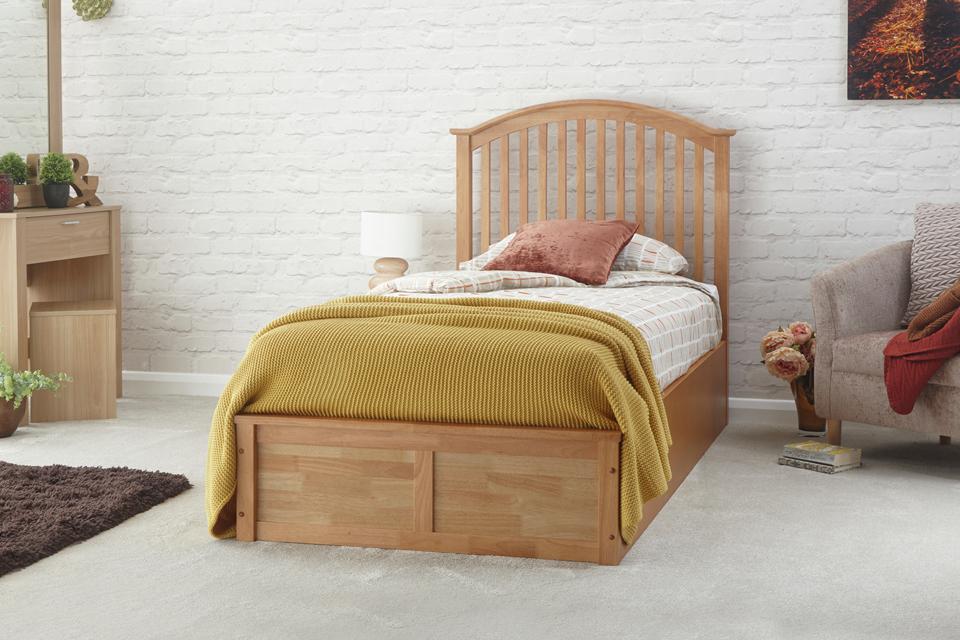An ottoman single bed frame in oak effect in a white bedroom.