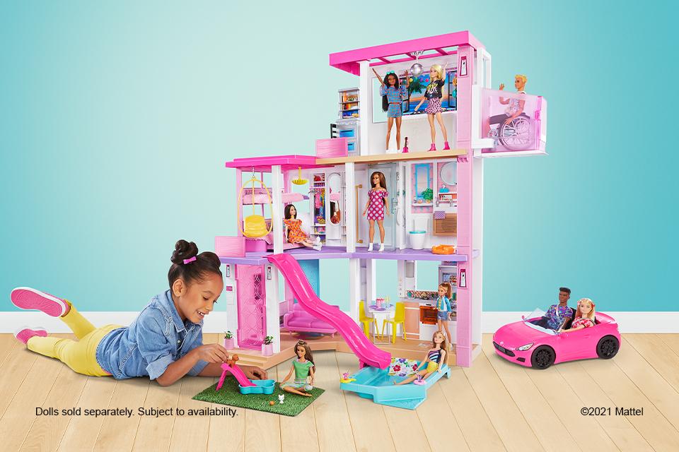 A girl playing with a tall Barbie day to night dreamhouse.