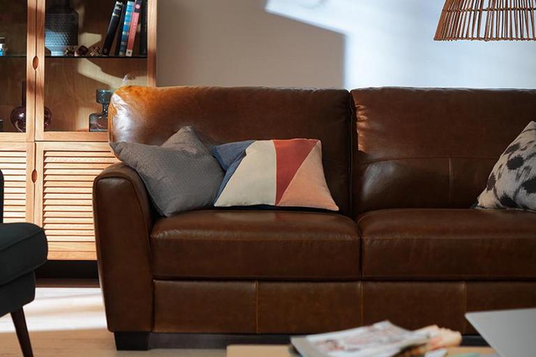 Image of a leather sofa with cushions in a living room.
