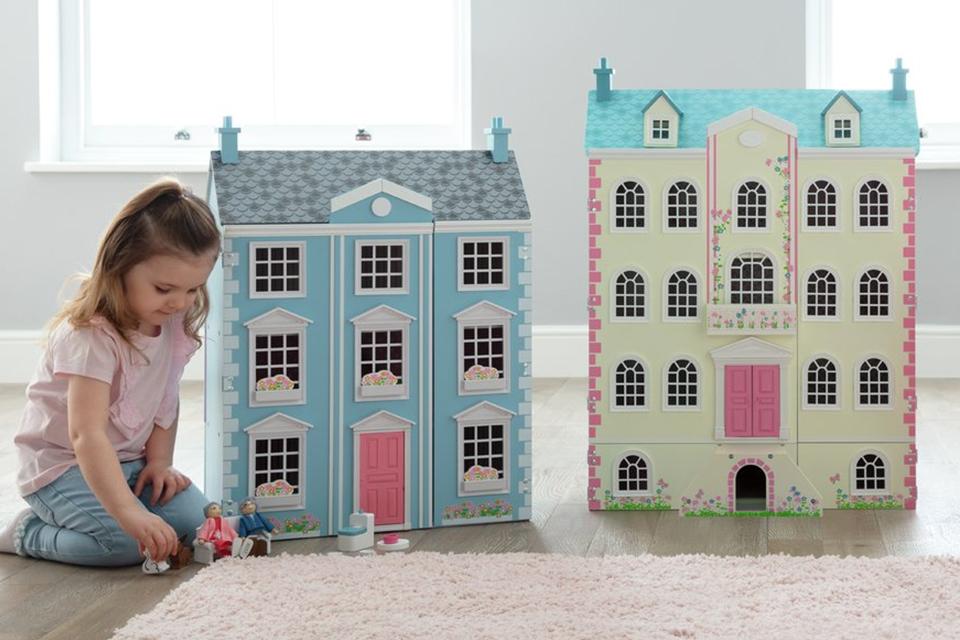 A toddler playing with a Liberty House kids dollhouse for books and toys.