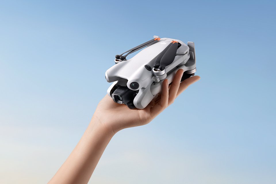 A person holding a DJI Mini Pro 4 camera drone. 
