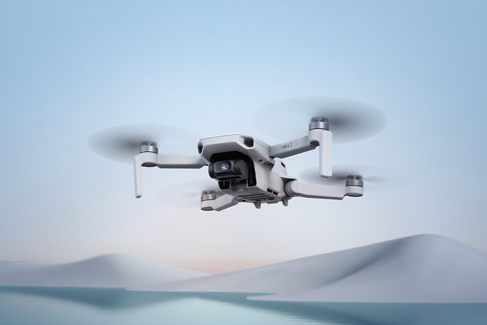 A DJI Mini 2 SE camera drone flying over water. 