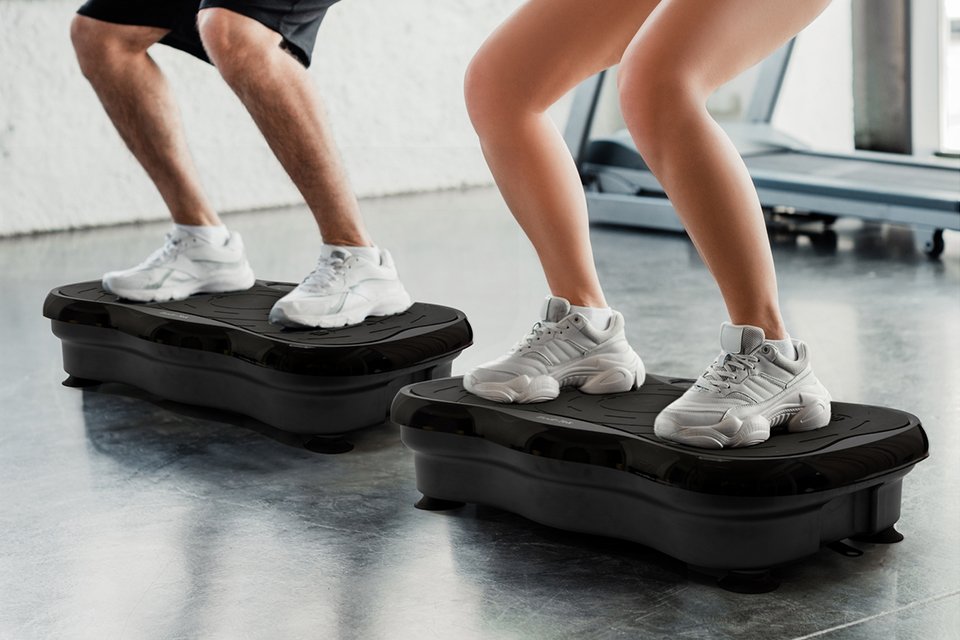 closeup image of two people using vibration plates in a gym setting