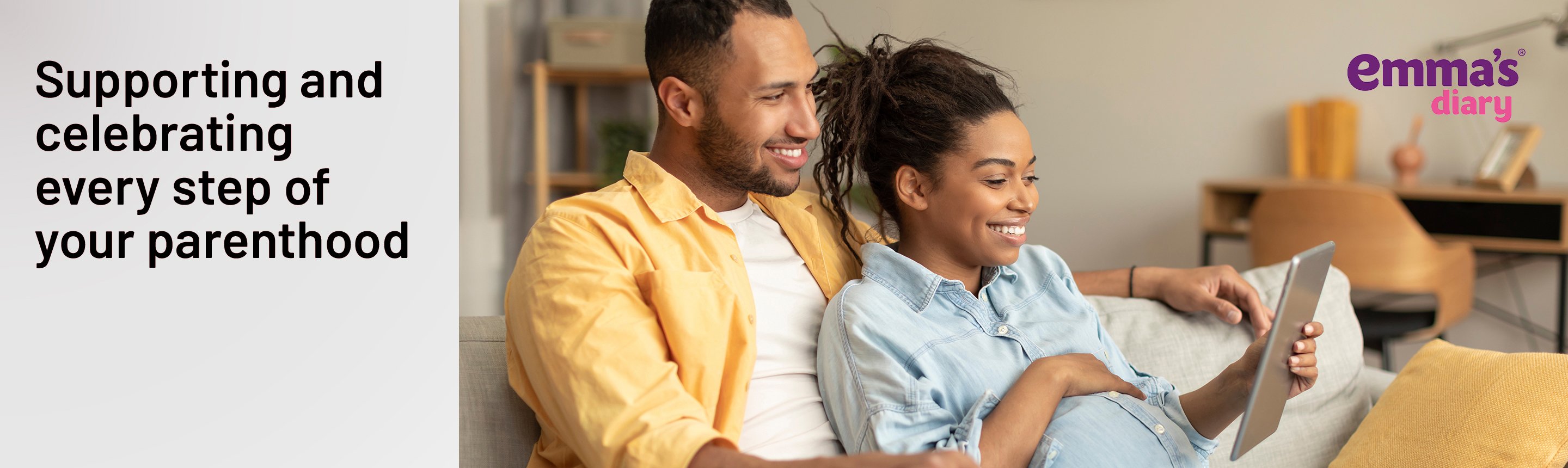 A pregnant couple looking at a tablet for baby related information.