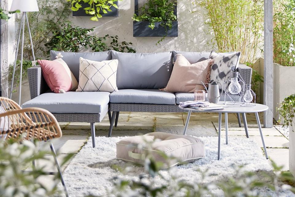 Rattan garden sofa with rug and coffee table.