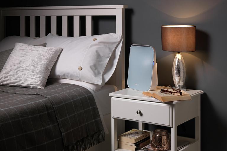 White bedside table with lamp and air purifier.