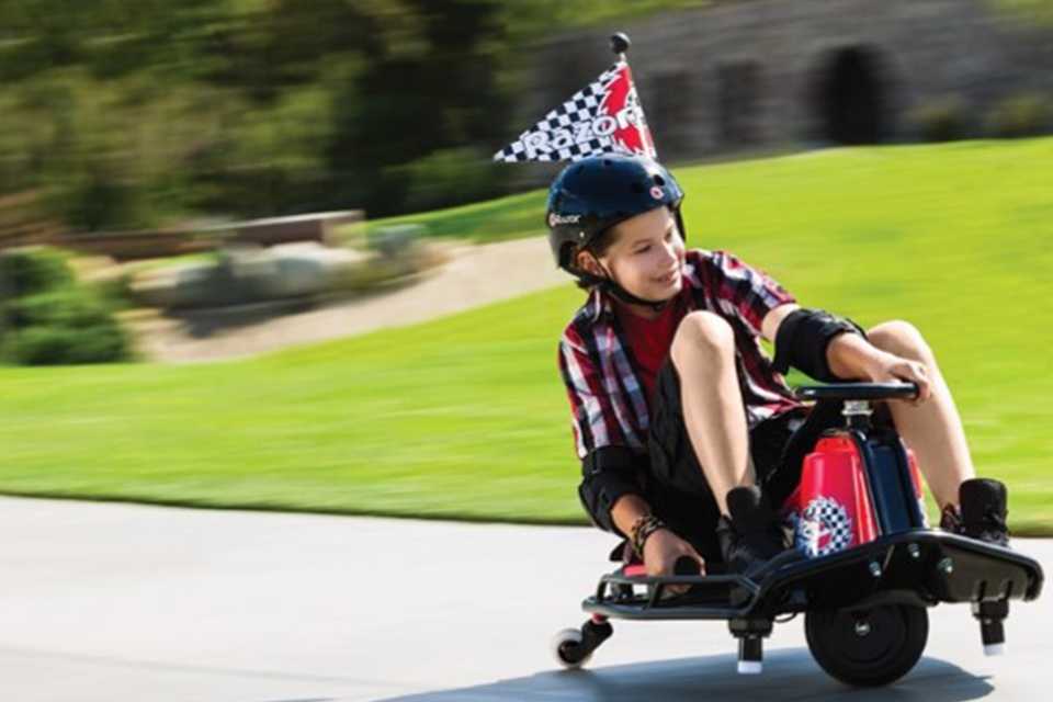 A young boy riding a Razor Crazy Cart.