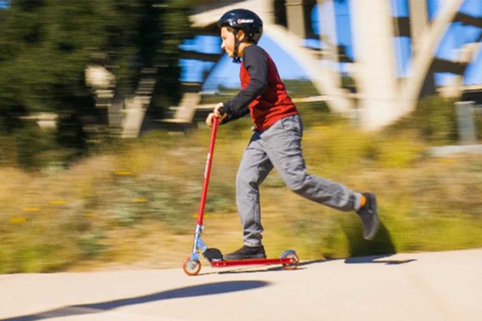 A young boy riding a Razor kick scooter.