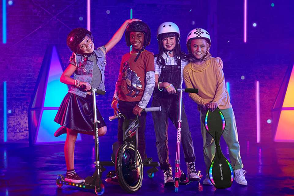 Four kids posing for a group photo with Razor Lighshow products including a skateboard and 3 electric scooters.