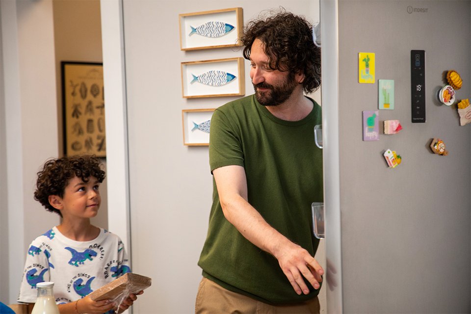 A father taking out food for his son from an Indesit fridge freezer.