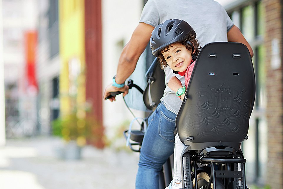 A father riding a bike with a little girl sitting in the rear bike seat for kids.