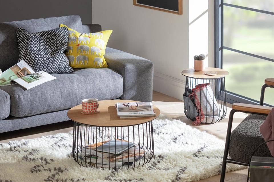 Image of two round, wired, black and wood coffee tables in living room setting.