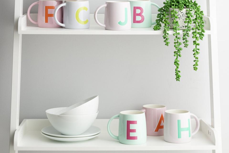 Mugs with alphabet letters on shelf.