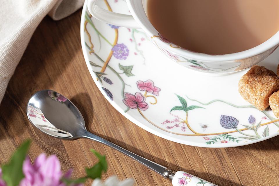 Close up on floral patterned teacup, saucer and spoon.