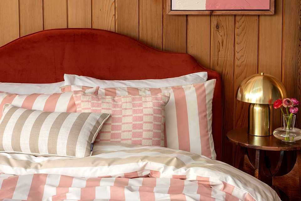  A pink and white striped bedding with pillows.