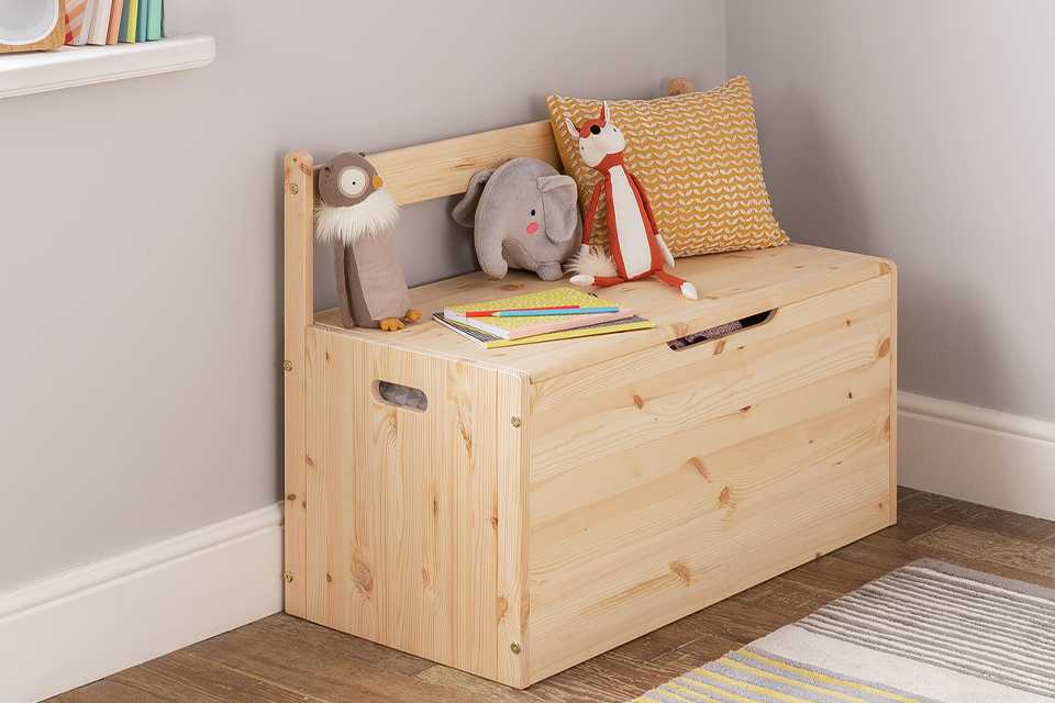 A cushion and soft toys on an Argos Home kids' Scandinavia extra large toy storage box.