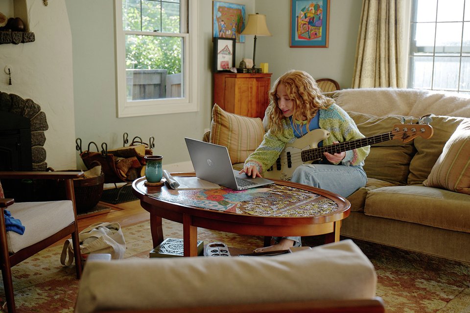 A girl learning how to play guitar through her Chromebook.