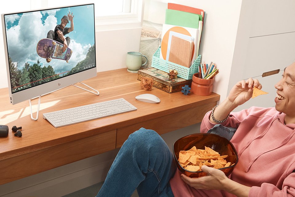 A man watching a video on HP 23.8in i3 8GB 256GB All-in-One PC.