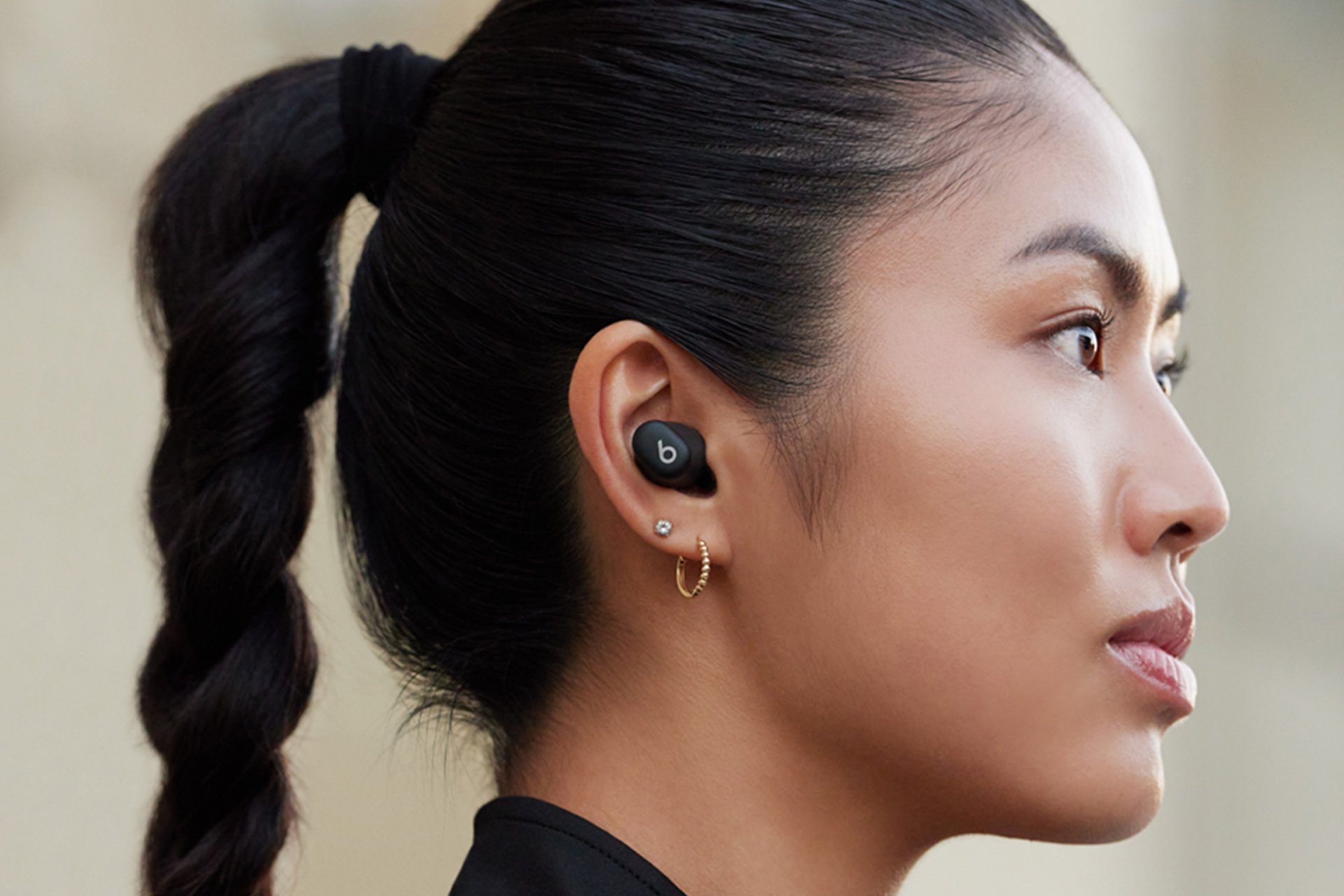  A woman wearing black Beats Studio earbuds. 