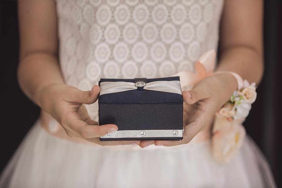 A woman in a wedding gown holding a gift box. 