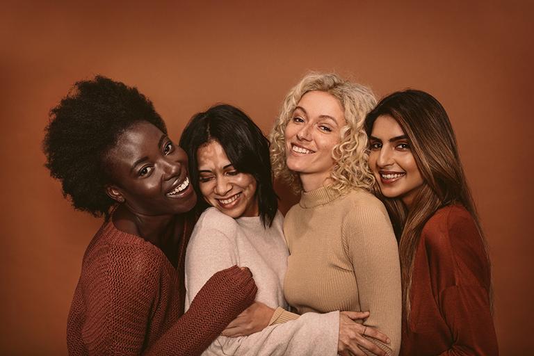 Four women with different hair styles hugging