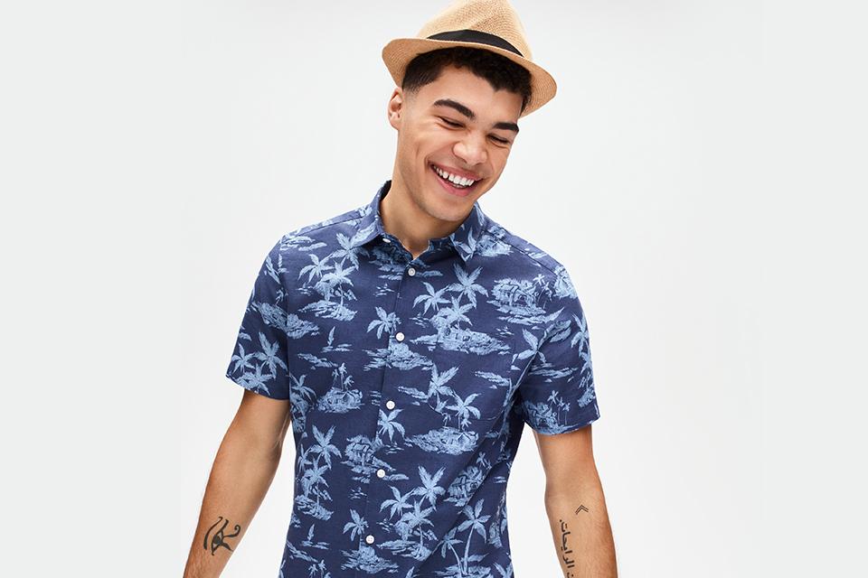 Male model in straw hat and blue printed tropical short-sleeved shirt. 