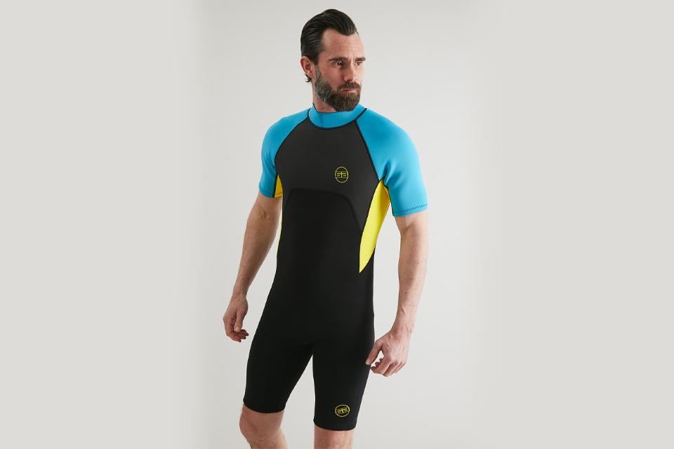 Male model in black, blue and yellow short wetsuit.