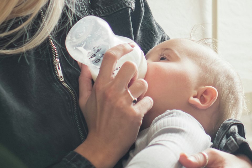A woman bottle feeding the baby.