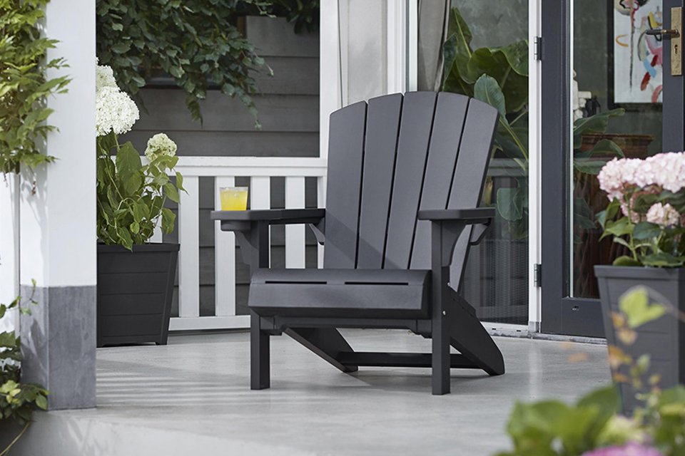 Keter Plastic Adirondack garden chair on patio with flowerpots placed on either side.