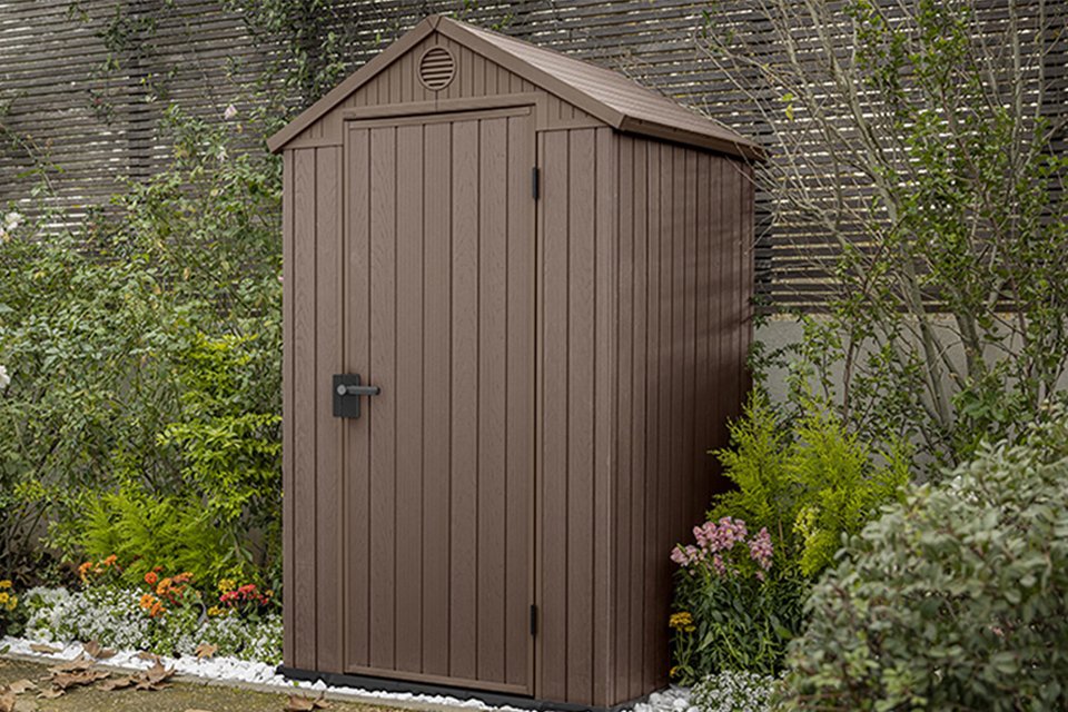 Keter Darwin Apex brown garden storage shed surrounded by plants.