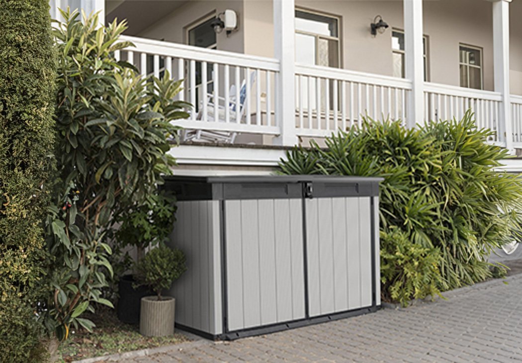 Keter Store It Out Premier Jumbo Grey garden storage shed placed beneath patio next to plants.