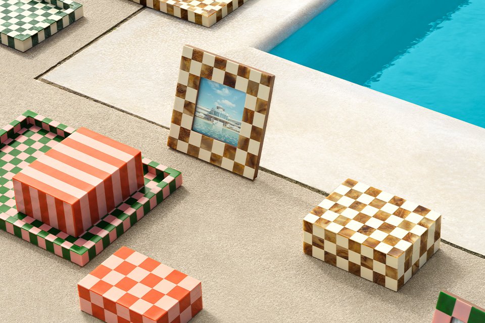 Habitat picture frames and trinket trays with colourful check patterns placed next to a pool.