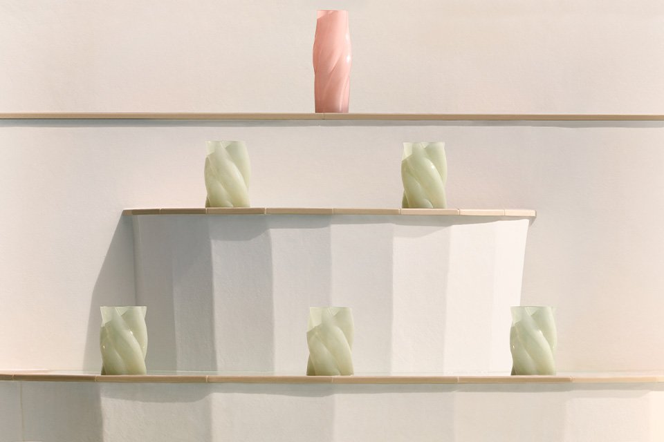 Habitat vases in white and pink placed on and around a white table next to a pool. 