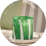 A large white and green Habitat large citronella multiwick candle with a striped effect on an outdoor patio set.