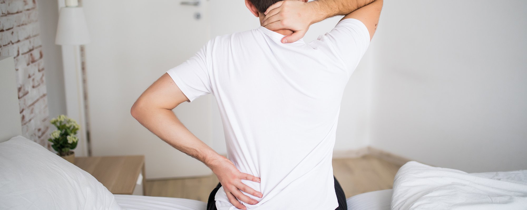 Man suffering from back pain at home in the bedroom.