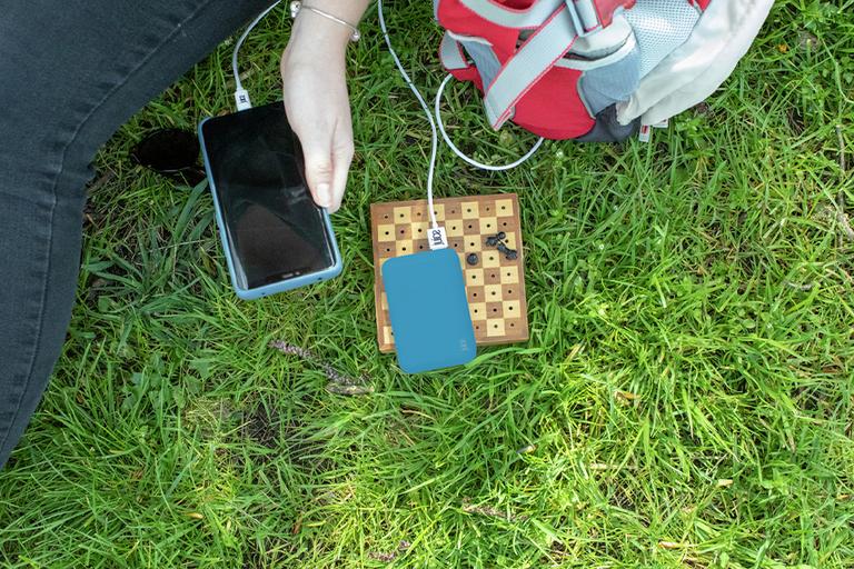 Mobile phone plugged into a blue power bank.
