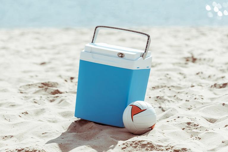 Blue coolbox on beach with volleyball.