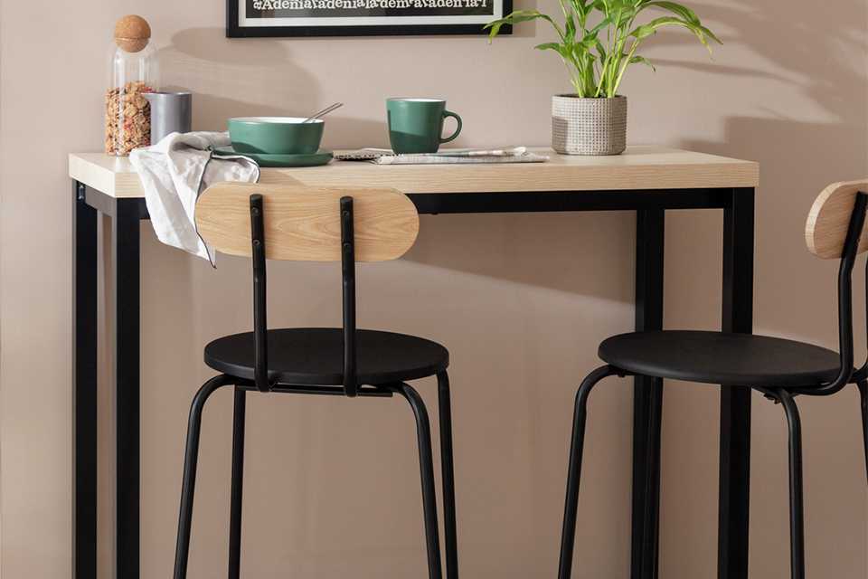 A Habitat Zayn wood effect bar table with 2 black bar stools. 