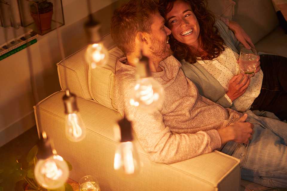 A couple sitting in a living room with LED lights on.