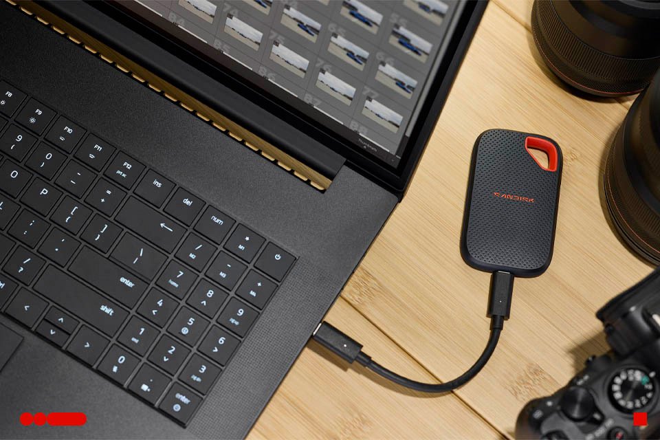 A SANDISK portable SSD connected to a laptop via a USB cable.