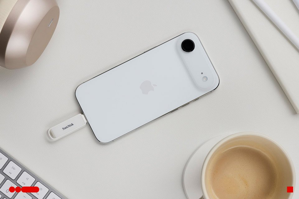 SANDISK phone drive with USB-C plugged into an iPhone placed on a desktop.