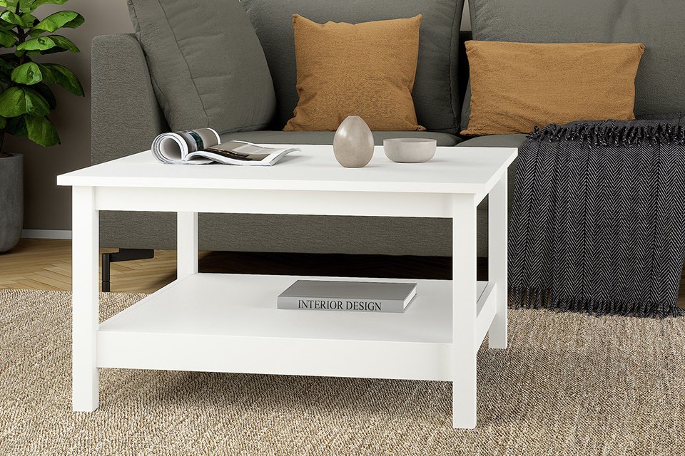 A Tvilum Madrid white coffee table placed in front of a white sofa in a living room.