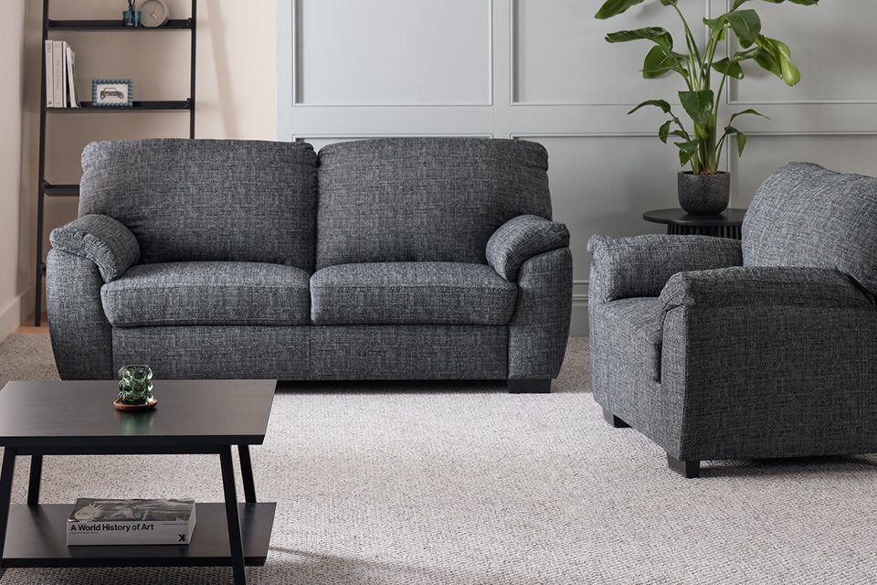 A charcoal Argos Home Milano Fabric chair and 3 seater sofa set in a living room next to a ladder shelf and a coffee table.