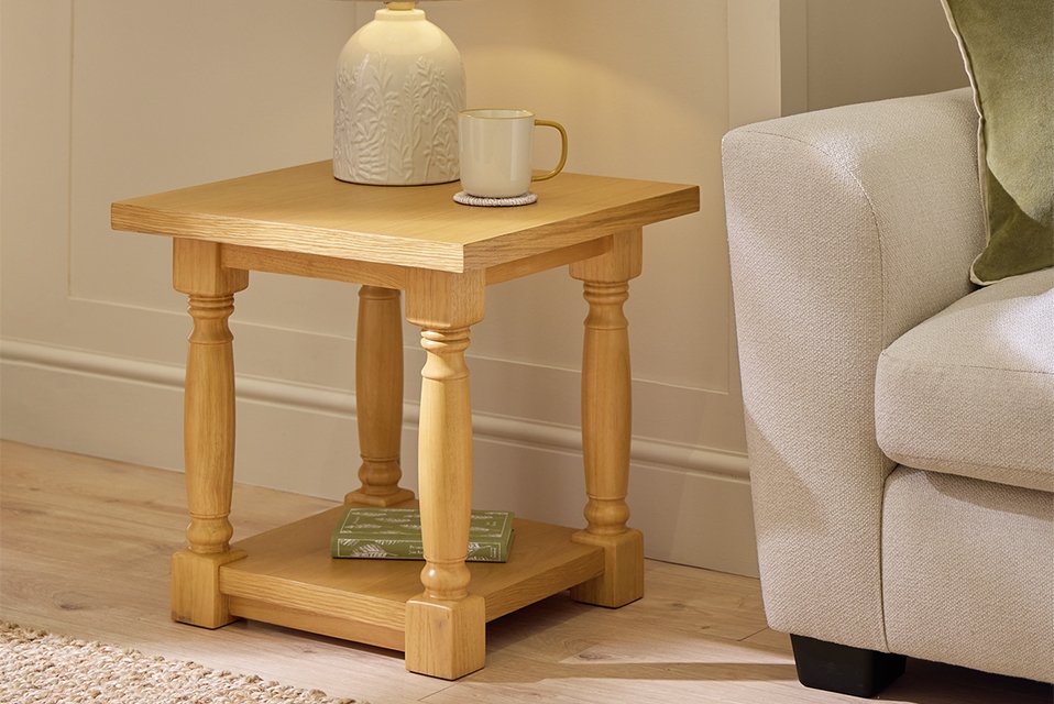 A natural Argos Home Raina side table next to a sofa in a living room.