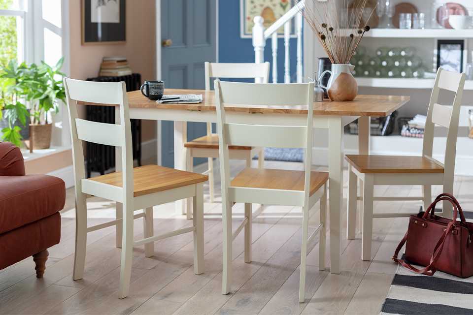 Oak and white dining tables with four matching chairs.