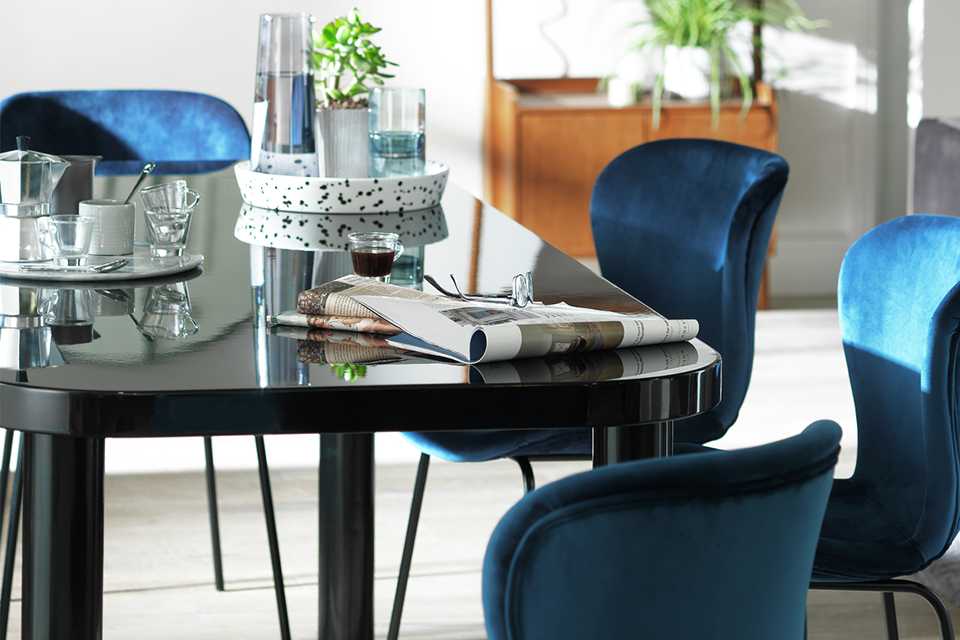 Black glossy dining table and blue velvet dining chairs.