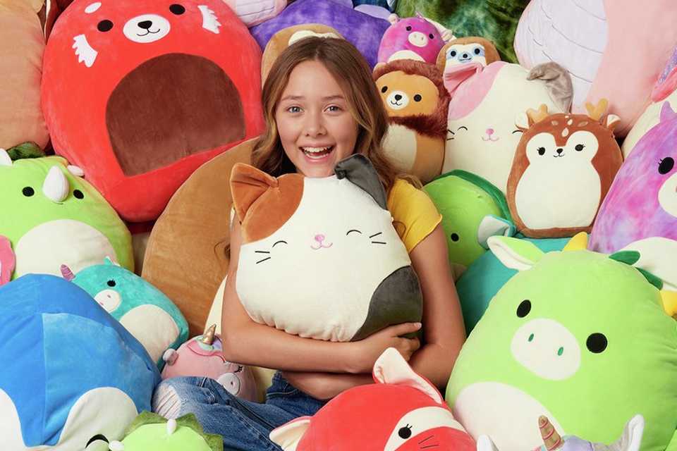 Girl surrounded by a collection of Squishmallows.