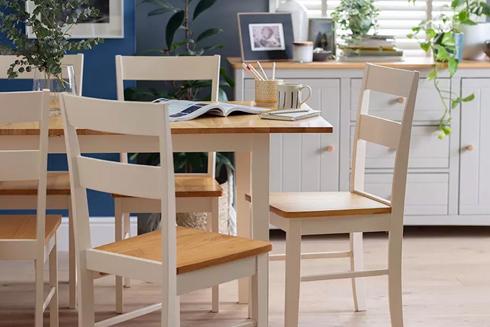 A white and natural wood rectangular dining set in a navy blue room.