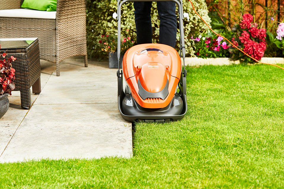 A person mowing a lawn using a Flymo® EasIGlide 330V hover lawnmower.